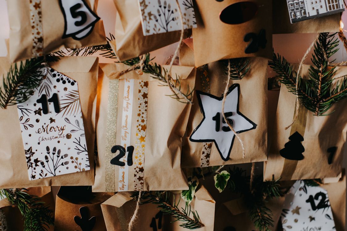 Nahaufnahme eines selbstgemachten Adventskalenders mit nummerierten Tüten und Tannenzweigen