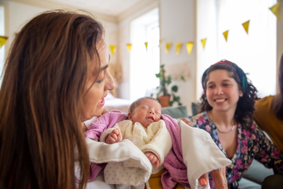 Eine Mutter hält ihr neugeborenes Baby, eingewickelt in ein weiches Tuch