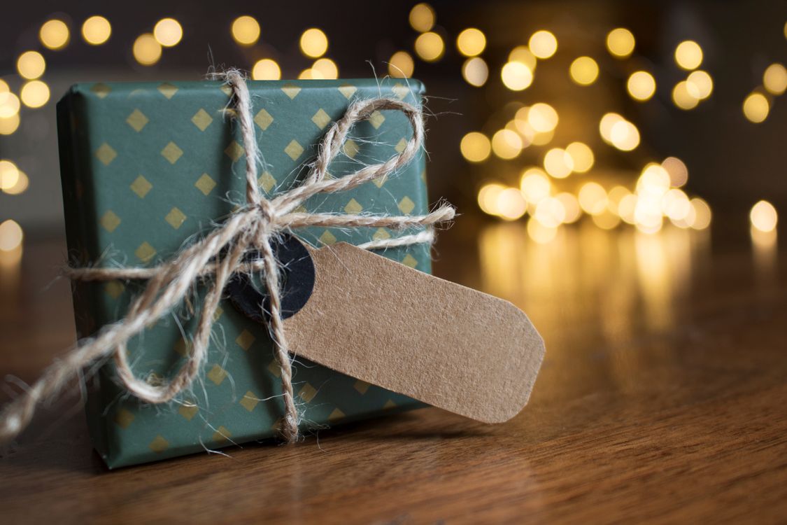 Ein eingepacktes Weihnachtsgeschenk neben warmen Lichtern
