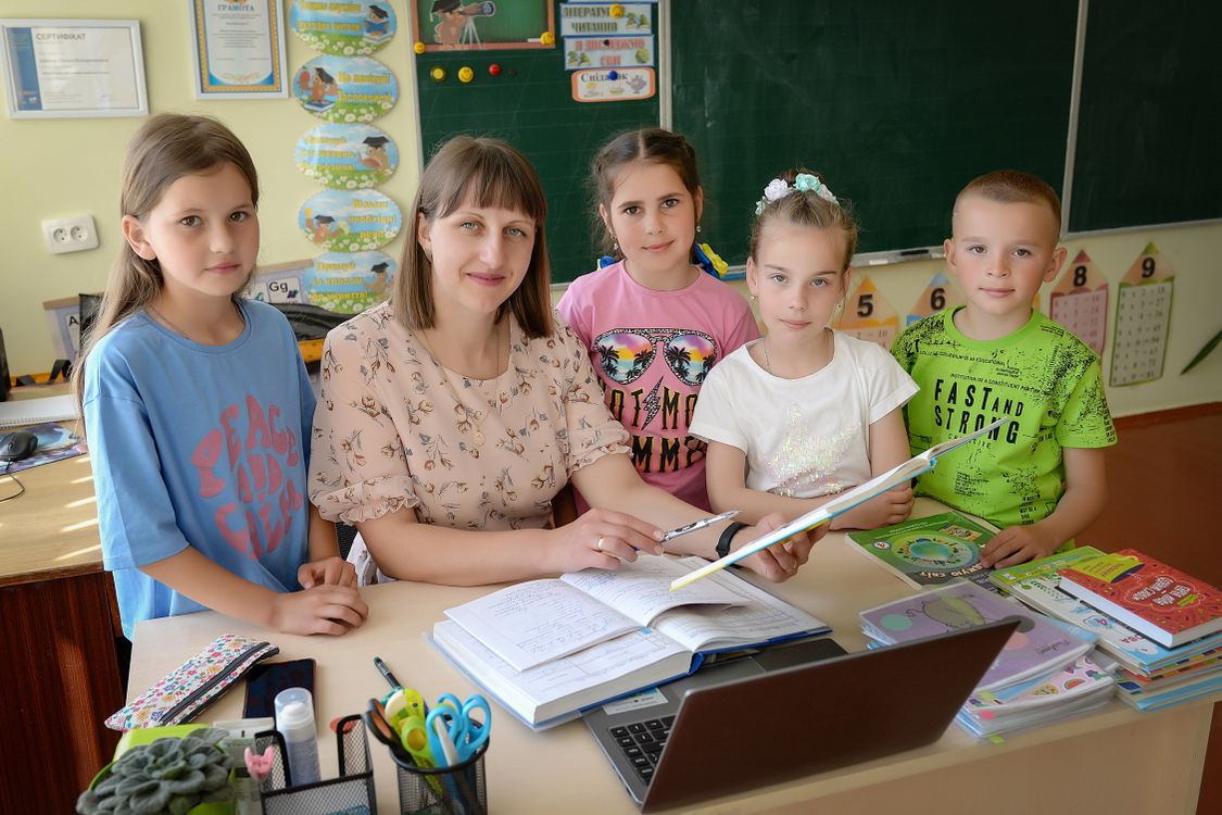 Kinder in einem Klassenzimmer hören aufmerksam ihrer Lehrerin zu