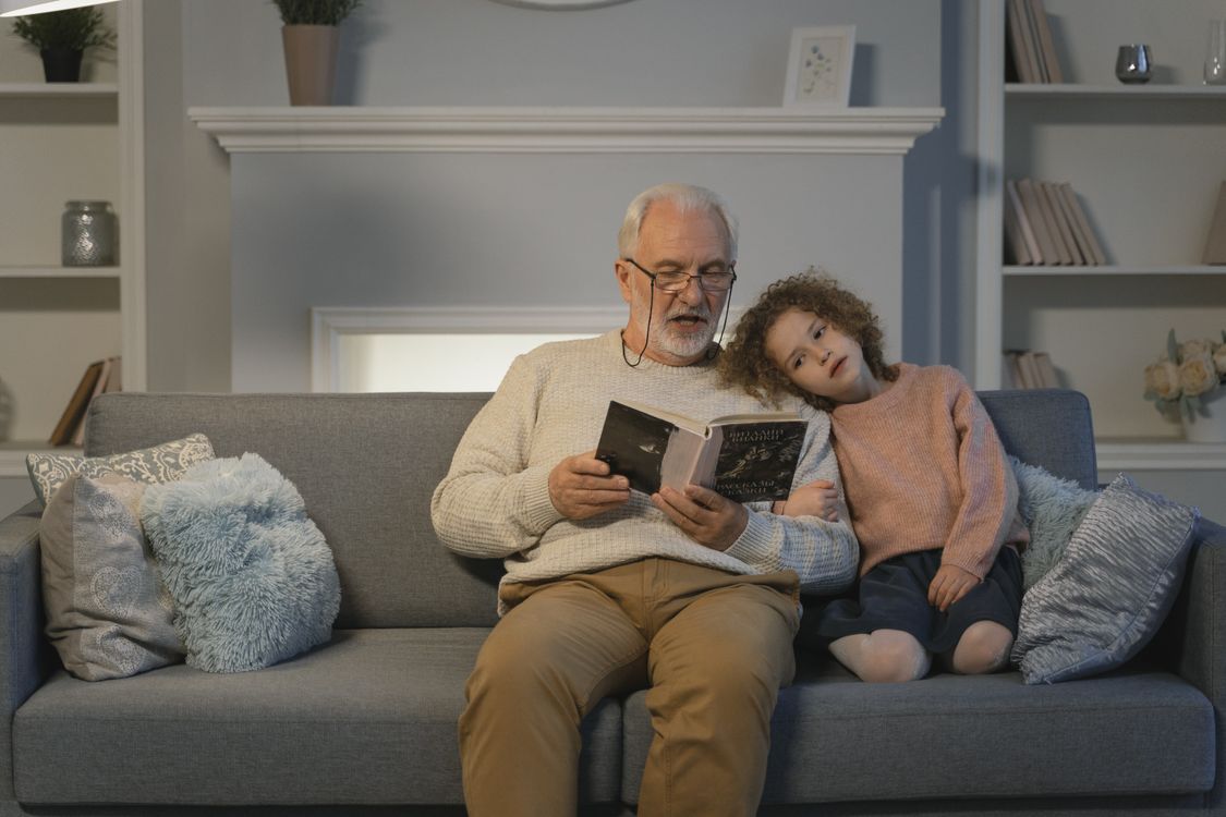 Großvater und Enkelin lesen gemeinsam auf dem Sofa