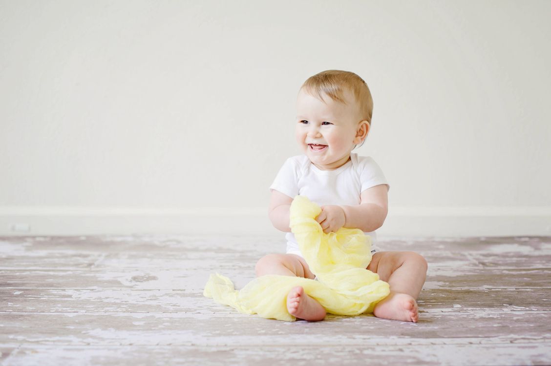Ein lachendes Baby auf einer gelben Decke